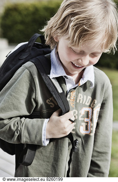 Little schoolboy with backpack smiling outdoors