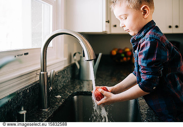 Little Toddler washing an apple before eating it.