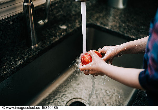 Little Toddler washing an apple before eating it.