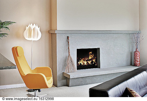 Living room in a modern house  with a fireplace and mantlepiece and hearth  and a modern yellow chair.