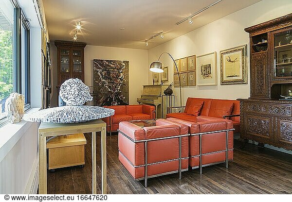 Living room with Le Corbusier (Imitation) orange leather sofas  armchairs  antique wooden buffet inside contemporary home decorated with paintings and sculptures by Armenian born Canadian artist Garen Bedrossian  Quebec  Canada. This image is property released for editorial use only. EUPR0360.