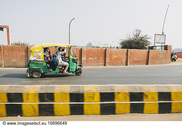 Local auto passing by the streets in Agra with a group of local Indian people.