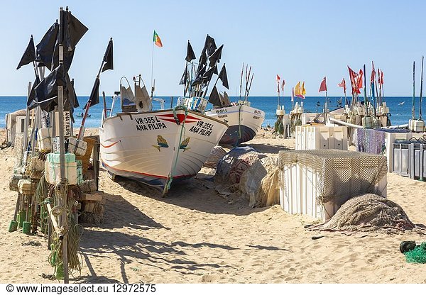 Local traditional style fishing boat with its fishing flags and floats on the beach at Monte Gordo  Algarve  Portugal.