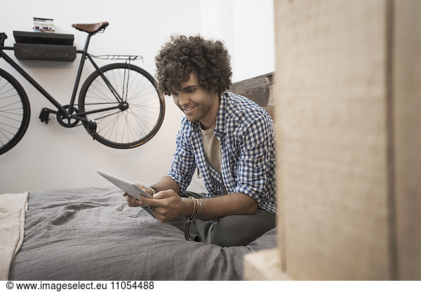 Loft-Wohnen. Ein Fahrrad  das an der Wand hängt. Ein Mann  der ein digitales Tablett benutzt.