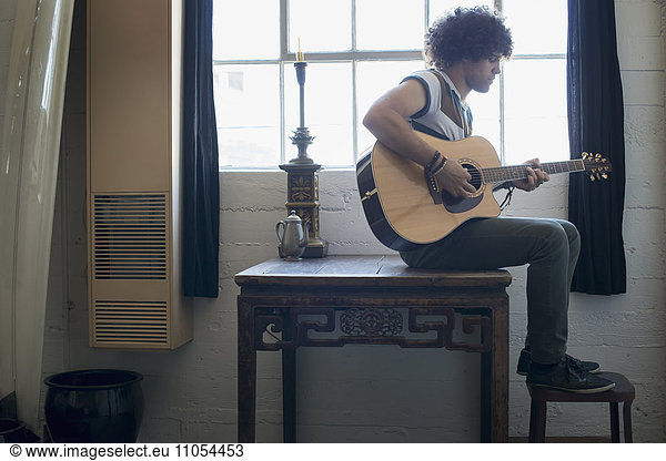 Loft-Wohnen. Ein junger Mann spielt Gitarre.