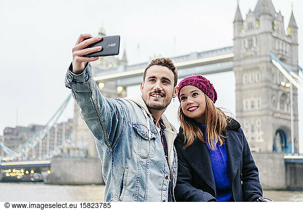 London  United Kingdom. A couple of boy and girl sitting next to London Bridge
