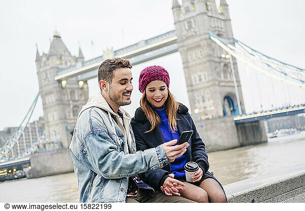 London  United Kingdom. A couple of boy and girl sitting next to Tower Bridge