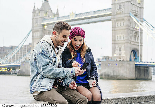 London  United Kingdom. A couple of boy and girl sitting next to Tower Bridge