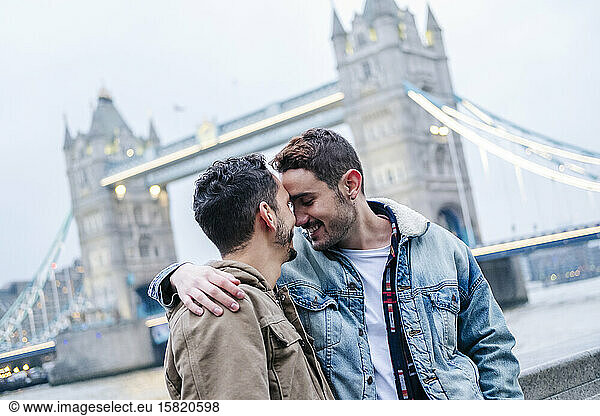London  United Kingdom  A couple of guys embracing in front of Tower Bridge