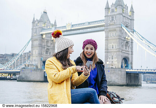 London  United KingdomTwo girls using smartphone in front of Tower Bridge