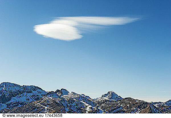 Lone cloud floating against clear sky over mountain peaks