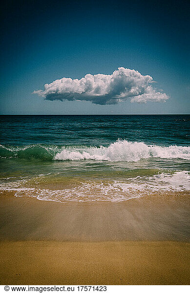 Lone Cloud Hovers over Blue Pacific waves and sand