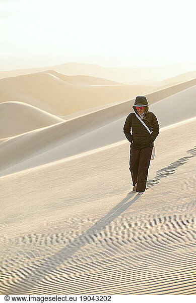 lone female in black puffy jacket walks alone in desert