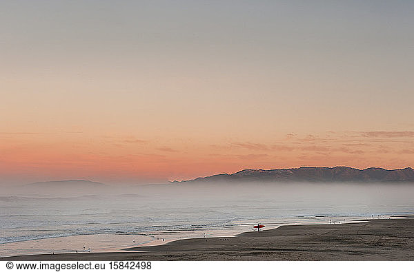 lone surfer checks surf at sunrise in California