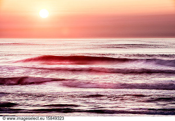 Lone surfer in water as sun sets in California