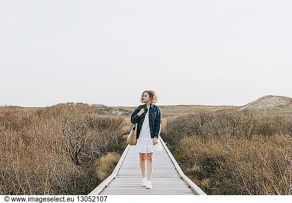 Lone young woman strolling on coastal dune boardwalk  Menemsha  Martha's Vineyard  Massachusetts  USA