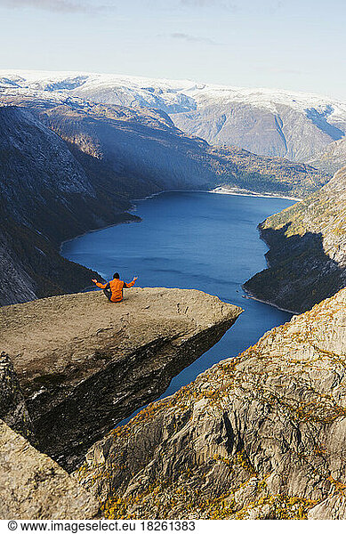 lonely hiker meditating on a huge rock of Trolltunga in Norway