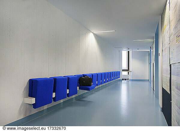 Long corridor in modern training college with blue seats.