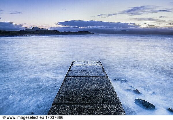 Long exposure calm tranquil scene of waves and the ocean with a pier at Criccieth Beach at sunrise  North Wales  United Kingdom