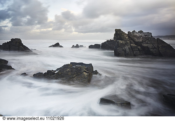 Long exposure ocean swirling around rocks  Devon  United Kingdom
