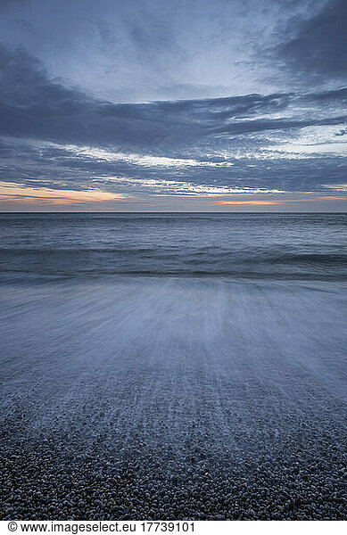 Long exposure of English Channel beach at dusk with clear line of horizon over sea in background