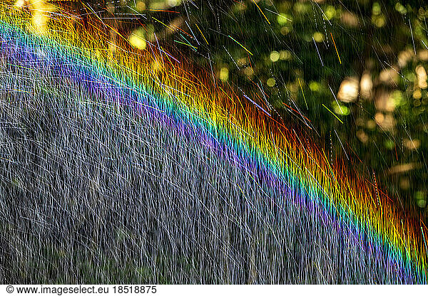 Long exposure of spray of water covered in rainbow colored light