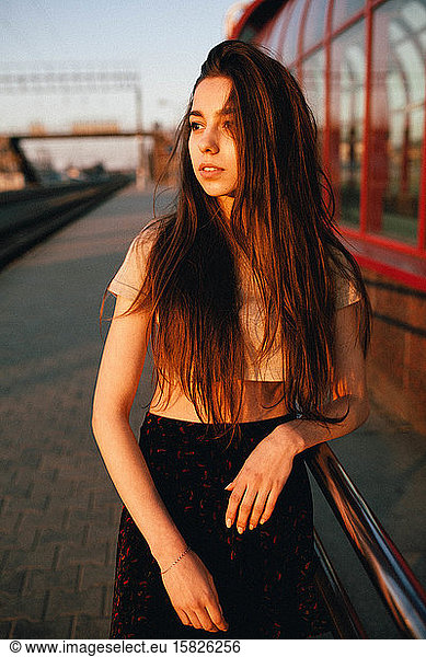long-haired woman stands at the train station