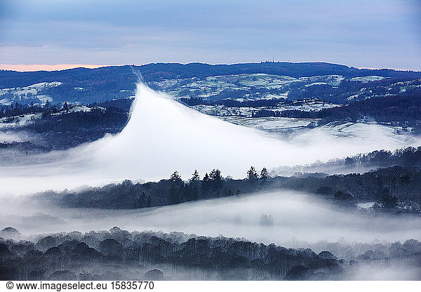 Looking down into the Langdale Valley above valley mist formed by a temperature inversion on Loughrigg  near Ambleside in the Lake District National Park. Localised warming has caused this ve