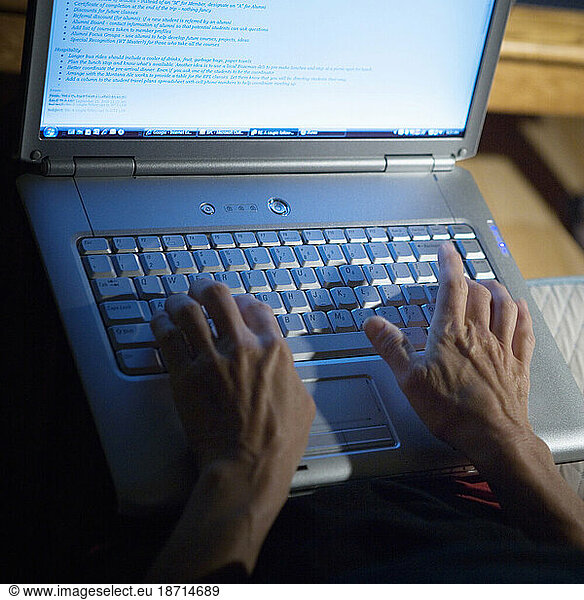 Looking down on a woman's hands on the keyboard of a laptop computer.