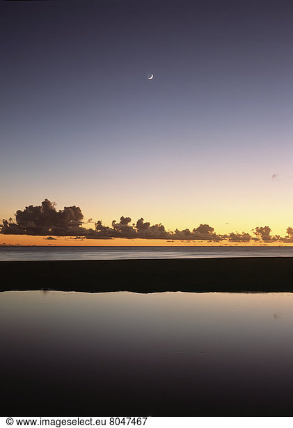 Looking over shallow pool at dusk to moon setting off West coast  Barbados