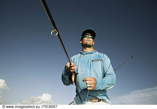Looking up at fisherman holding fly line looking out at the water