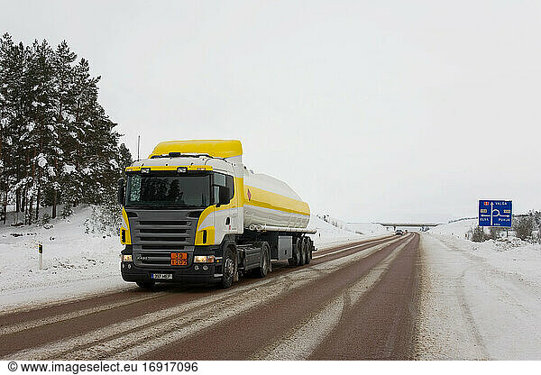 Lorry driving on snowy rural road.
