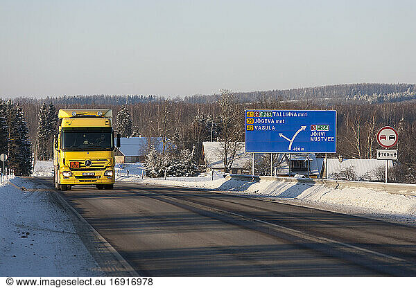 Lorry driving on snowy rural road woith road sign.