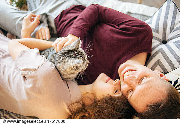 Lovely couple stroking cat lying on bed