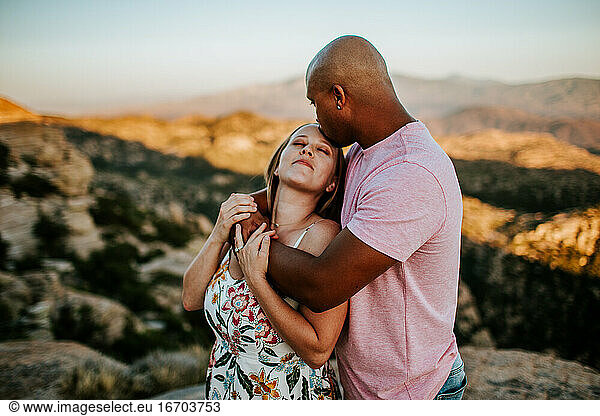 Loving couple hugging and kissing on top of mountain
