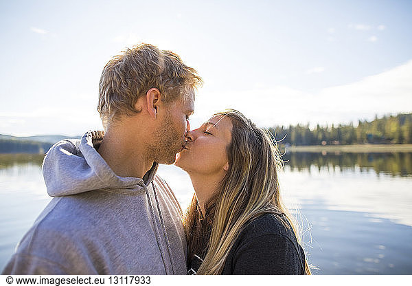 Loving couple kissing on mouth against lake