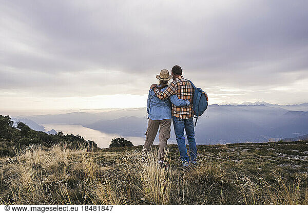 Loving couple standing with arms crossed on mountain
