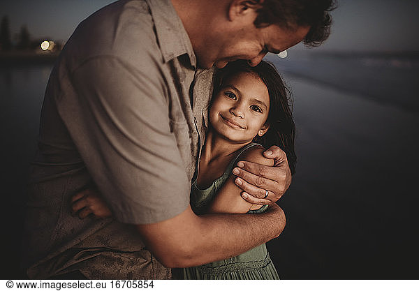 Loving father embracing beautiful 8 yr old daughter with dark eyes