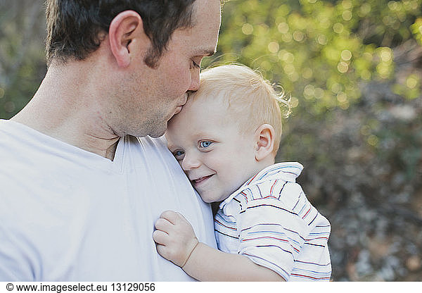 Loving father kissing son on forehead at park