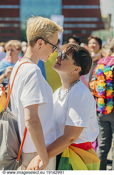 Loving lesbians standing and embracing each other at gay pride event