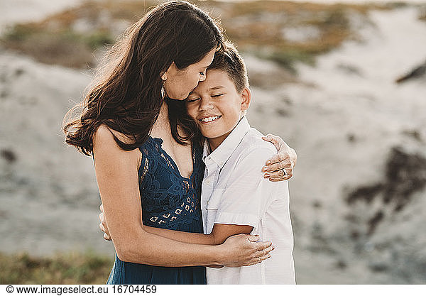 Loving mother embraces smiling preteen son