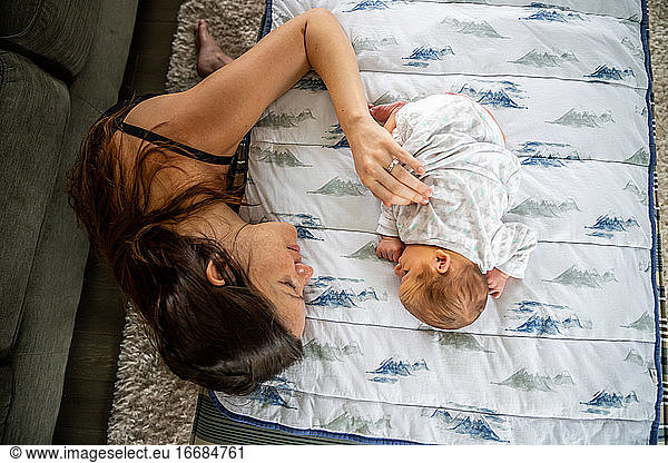 Loving mother gently touching newborn baby laying on stomach.