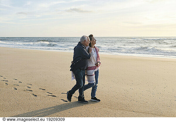 Loving senior couple walking on sand at beach