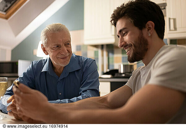 Loving senior father communicating with son with smartphone