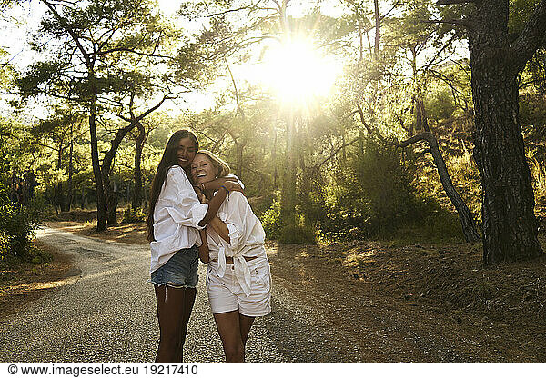 Loving teenage girl hugging mother standing on road at forest