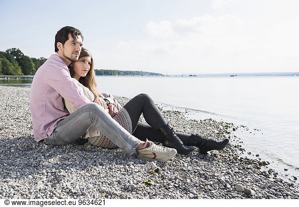 Loving young couple sitting shore lake