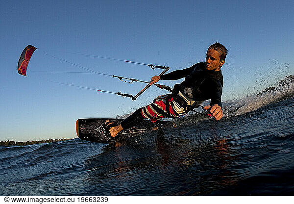 Low angle perspective of a kiteboarder carving by in nice light.