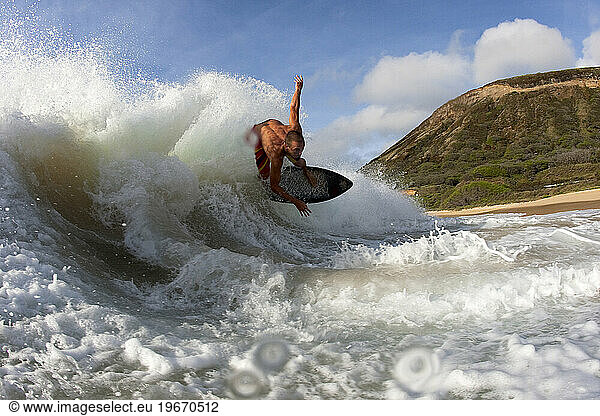 Low angle perspective of one man skimboarding into the barrel of a wave.