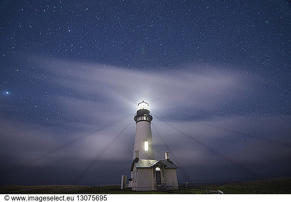 Low angle scenic view of Yaquina Head Lighthouse on shore against star field