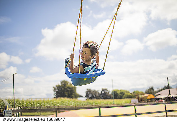 Low angle view of boy swinging outdoors.